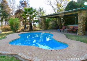 a swimming pool in a patio with a table and chairs at Ardmore Guest Farm in Champagne Valley