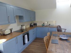 格拉斯顿伯里The Woodshed - A newly built, 2 bedroom, cottage near Glastonbury的配有蓝色橱柜和木桌的厨房 更多10张照片