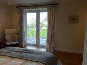 a bedroom with a bed and a sliding glass door at The Woodshed - A newly built, 2 bedroom, cottage near Glastonbury in Glastonbury