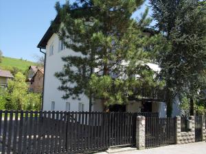 a white house with a fence and a tree at Apartment Zupan in Maribor