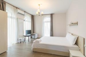 a white bedroom with a bed and a television at Villa Ciao - Adults Only in Corbu