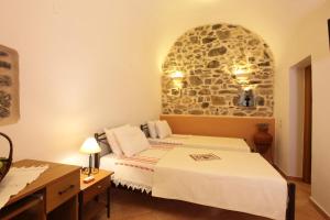 a bedroom with two beds and a stone wall at STOES Traditional Suites in Mesta