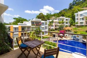 Kamala Hills Serviced Apartments في شاطئ كامالا: بلكونه مع طاوله وكراسي ومسبح