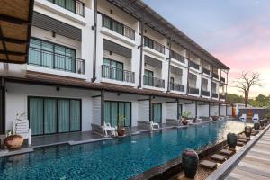 a swimming pool in front of a building at Phuketa - SHA Extra Plus in Phuket