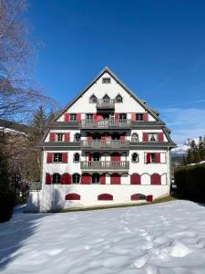 um grande edifício branco com janelas vermelhas na neve em Appartement Odyssée - Welkeys em Megève