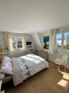 um quarto com uma cama, uma cadeira e janelas em Appartement Odyssée - Welkeys em Megève