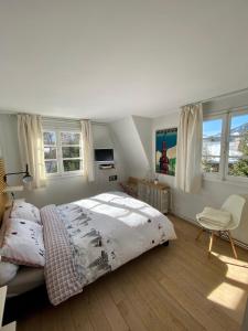 a bedroom with a bed and a chair and windows at Appartement Odyssée - Welkeys in Megève