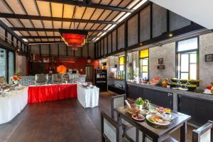 a restaurant with tables and a bar in a room at Phuketa - SHA Extra Plus in Phuket