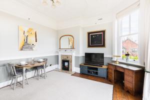 een woonkamer met een tafel, een televisie en een open haard bij Warwick Victorian Apartment in Warwick