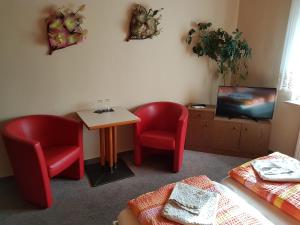 a room with two chairs and a table and a tv at Hotel Arkona in Genthin