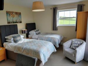 a bedroom with two beds and a chair and a window at Ghyll Beck House bed and breakfast in Leck