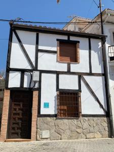 a white and black building with a window at Casa Cueva Castillo in Perales de Tajuña
