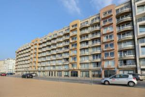 un grand bâtiment avec des voitures garées devant lui dans l'établissement Apartment "Zeezicht", à Ostende