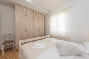 a white bedroom with a bed and a chair at Apartment Miriam with grill and terrace - by TA Leut Agency in Privlaka