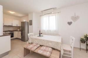 a kitchen with a table and chairs and a refrigerator at Apartment Miriam with grill and terrace - by TA Leut Agency in Privlaka