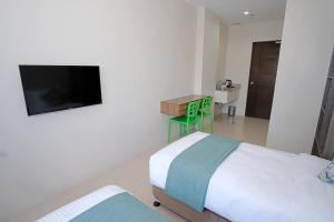 a bedroom with a bed and a flat screen tv at Sukro in Bacolod