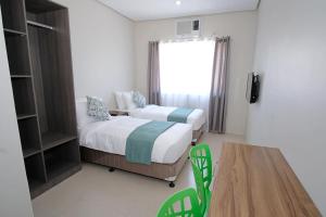 um quarto com duas camas e uma mesa e uma janela em Sukro em Bacolod
