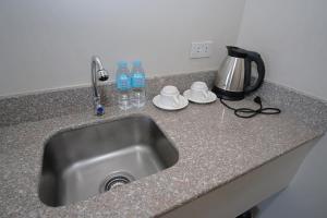 a kitchen counter with a sink and a kettle and water bottles at Sukro in Bacolod