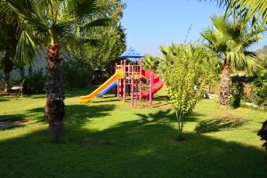 a playground with a slide in a park with palm trees at Adrasan Beach Club in Adrasan