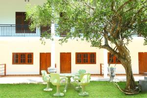 un tavolo e sedie sotto un albero in un cortile di Emerald Guest House a Kataragama