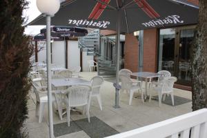um pátio com mesas e cadeiras e um guarda-sol em Ummen Hotel&Restaurant em Barßel