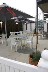 a patio with white tables and chairs and an umbrella at Ummen Hotel&Restaurant in Barßel