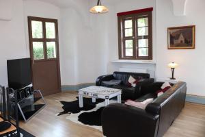 un soggiorno con 2 divani e una TV di Ferienwohnung-im-Pfarrhaus a Müglitztal