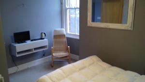 a bedroom with a bed and a chair and a mirror at Lansdown House Bed & Breakfast in Market Drayton