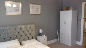 a bedroom with a bed with a headboard and a cabinet at Lansdown House Bed & Breakfast in Market Drayton