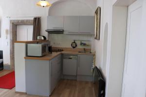 eine kleine Küche mit weißen Schränken und einer Mikrowelle in der Unterkunft Ferienwohnung im Pfarrhaus in Müglitztal