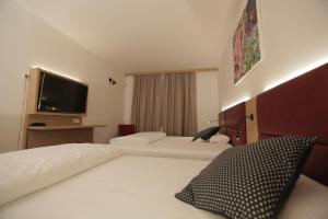 a hotel room with two beds and a flat screen tv at Galeria Airport Hotel in Mörfelden-Walldorf