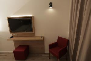 um quarto com uma televisão e uma cadeira vermelha em Galeria Airport Hotel em Mörfelden-Walldorf