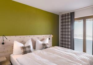 a bedroom with a white bed with a green wall at Gipfelrestaurant Fronalpstock in Stoos