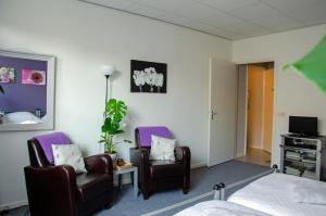 - une chambre avec deux chaises, un lit et une télévision dans l'établissement Vakantiewoning De Berkeboom, à Winterswijk