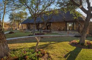 un edificio con tetto di paglia in un parco di Thornhill Guest House in the middle of a nature reserve a Hoedspruit