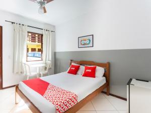 a bedroom with a bed with red and white pillows at OYO Hotel Recanto Do Alto, Teresópolis in Teresópolis
