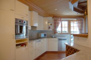 kuchnia z białymi urządzeniami i drewnianym sufitem w obiekcie Chalet Obelix w mieście Grindelwald