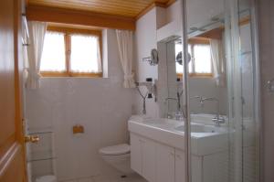 Chalet Obelix في جريندلفالد: حمام أبيض مع حوض ومرحاض