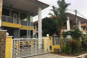 馬西的住宿－Pasir Gudang Marissa Homestay，黄色的房子,有白色的大门和棕榈树