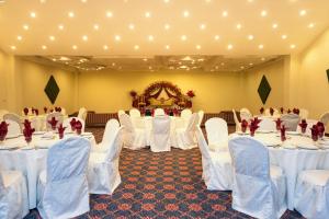 a banquet hall with white tables and white chairs at Hotel One Faisalabad in Faisalabad