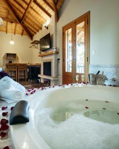 une grande baignoire entourée de pétales de rose rouge dans l'établissement Chalés Vila do Moinho, à Monte Verde