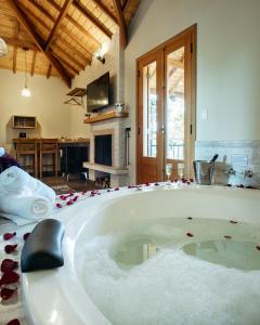 a large bath tub with red rose petals around it at Chalés Vila do Moinho in Monte Verde