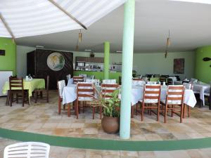 un ristorante con tavoli e sedie bianchi e pareti verdi di Arituba Tropical a Nísia Floresta