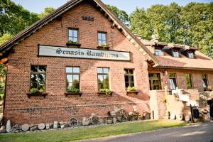 a red brick building with a sign on it at Senasis Rambynas in Lumpėnai