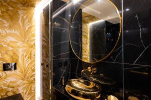 een badkamer met een gouden wastafel en een spiegel bij Golden Eye Apartament Seaside Park in Kołobrzeg