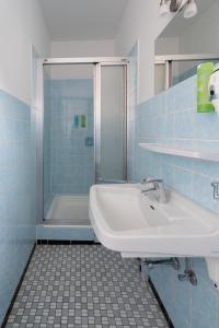 uma casa de banho em azulejos azuis com um lavatório e um chuveiro em Ferienwohnung Hochgefühl em Hohegeiß