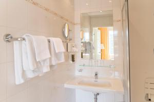 ein weißes Badezimmer mit einem Waschbecken und einem Spiegel in der Unterkunft Hotel Landsitz Pichlschloss in Neumarkt in Steiermark