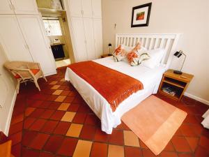 Un dormitorio con una gran cama blanca y una mesa en Jonquil Guest Cottage en Franschhoek