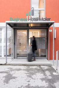 una persona in piedi di fronte a un negozio di Business Hotel Maier - kontaktloser Check-in a Götzis