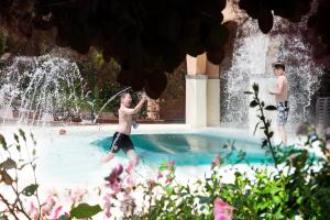 Zwei Jungs spielen in einem Springbrunnen im Schwimmbad in der Unterkunft Villa Norcenni ApartHotel in Figline Valdarno